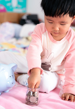 把硬幣放入玻璃瓶的中國小女孩
