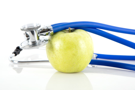 白背景上的青苹果和听诊器