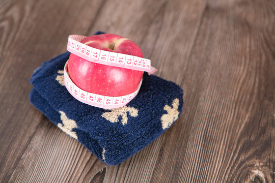 毛巾上一个被软尺缠绕的红苹果