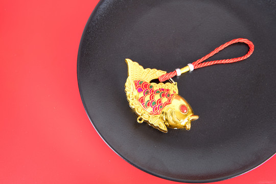 红背景上盘子里的金鱼挂件