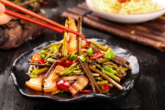 筷子夹着蕨菜炒肉