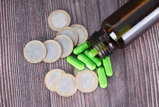 药瓶中倒出的绿色胶囊和欧元硬币