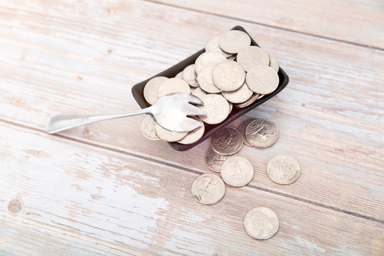 桌子上盛满美元硬币的小碟子