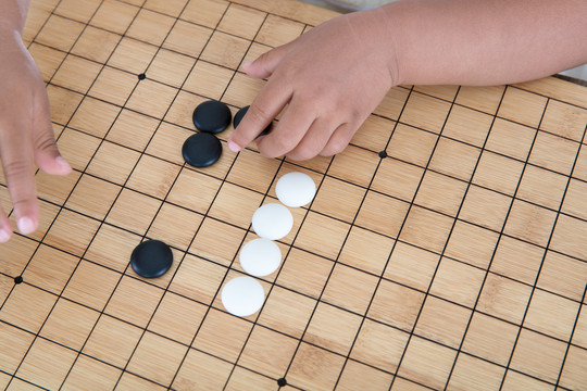 手拿着棋子在围棋棋盘上下棋