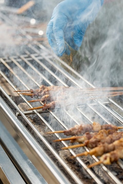 给正在炉子上烧烤的肉串撒调料