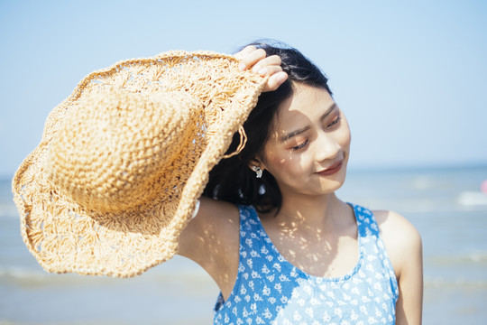 可爱的黑发女孩高举帽子，以防夏日阳光直射。