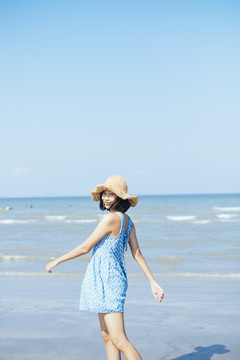下午站在海滩上的可爱的亚洲女孩。