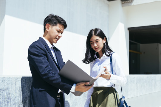 由于他们的重要项目，男人把文件给女人看。