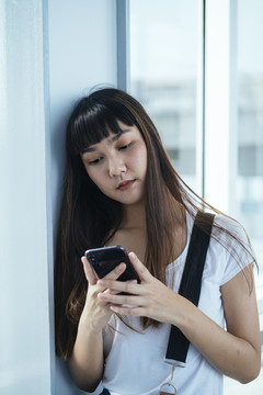 在大楼内使用手机拍摄的留着刘海发型的泰国年轻女士的肖像。