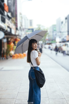 丽莎。在喜怒无常的日子里，一位留着刘海发型、手持雨伞的泰国年轻美女的肖像。