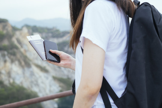 年轻的亚裔泰国人留着黑色长发，持泰国护照旅行的旅行家妇女