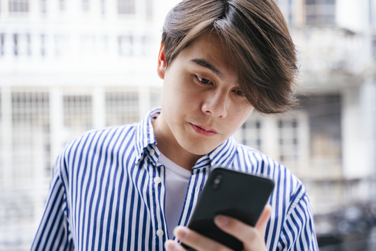 亚洲年轻人在户外街头使用智能手机。