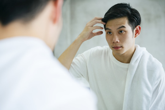 亚洲年轻人在洗澡后对着镜子看自己，找出错误，以使自己变得更好。