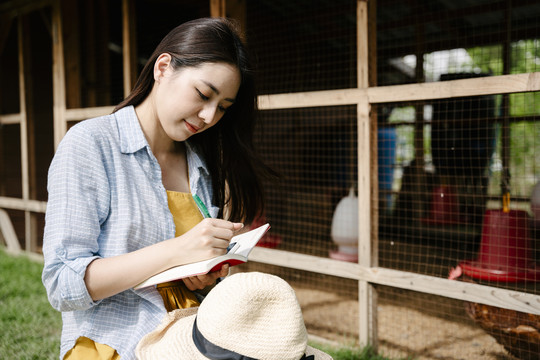 亚洲农妇在自家鸡舍里检查鸡肉。