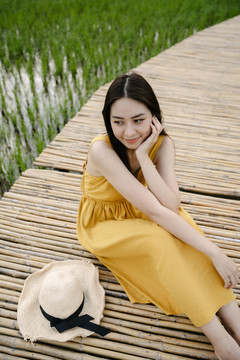 美丽的亚洲旅行家女子坐在稻田里的木桥上。