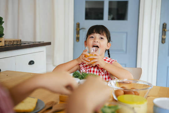亚洲小孩和家人在家里的厨房里吃早餐。