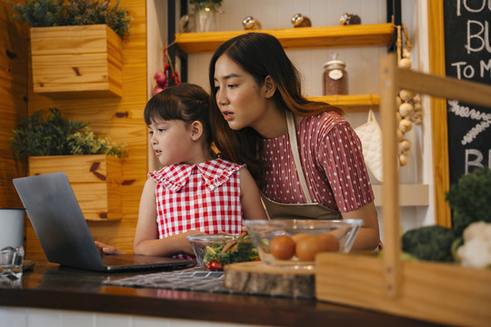 亚洲母女一边做饭一边在网上看菜谱。