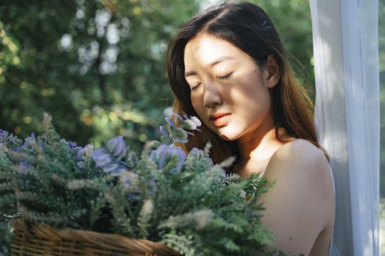 坐在花园里拿着花篮的年轻亚洲妇女的肖像。