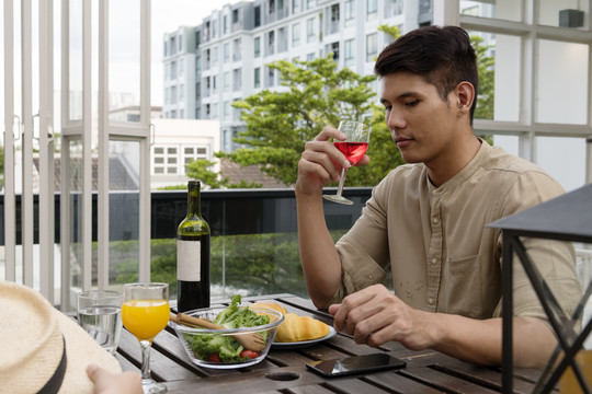 一名亚洲男子在咖啡馆和女友喝红酒。