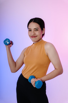 快乐的运动型亚洲女性用哑铃锻炼身体。