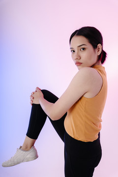 运动前伸展腿部的亚洲健康女性肖像。
