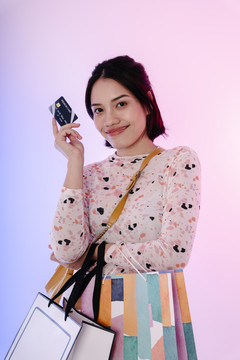 快乐的亚洲黑发女人喜欢用信用卡购物。购物袋模型设计。