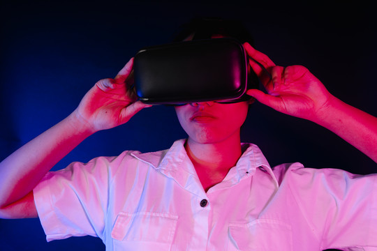 亚洲女性佩戴现代VR护目镜，与游戏或3D视频交互。