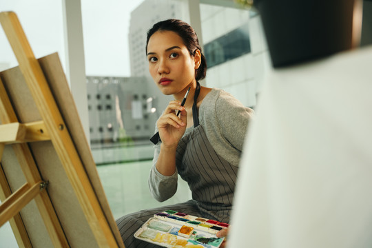 女艺术家在画室的帆布架上画彩色油画。