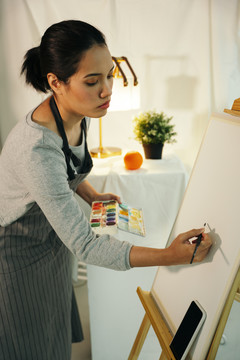 女艺术家在画室的帆布架上画彩色油画。