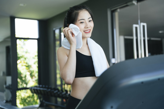 健康的亚洲女性在健身房的跑步机上跑步。