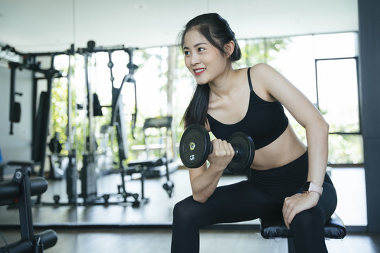 健康的亚洲女性在健身房练习哑铃的肖像。