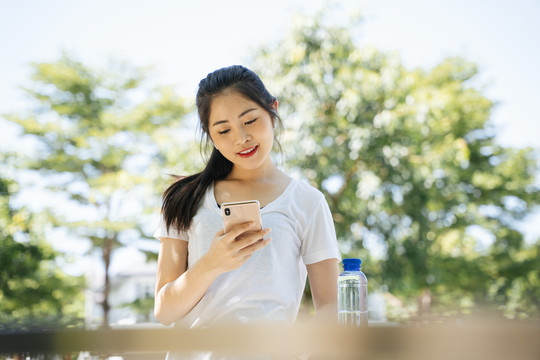健康的亚洲女性在跑步后使用智能手机。