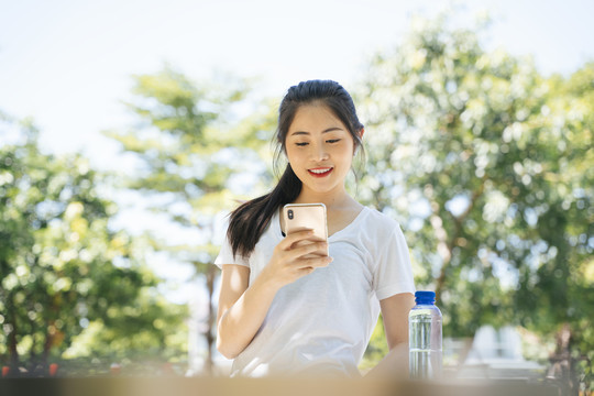 健康的亚洲女性在跑步后使用智能手机。