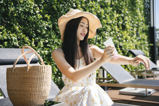 美丽的亚洲女性旅行者在身体皮肤上涂抹白色乳液。