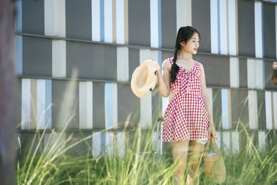 美丽的亚洲年轻女旅行者，穿着粉色连衣裙，带着旅行行李。