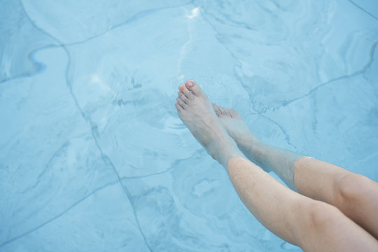 女人的腿喜欢在游泳池里打水。