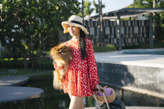 美丽的亚洲女旅行者带着她的狗在度假村和酒店里旅行。