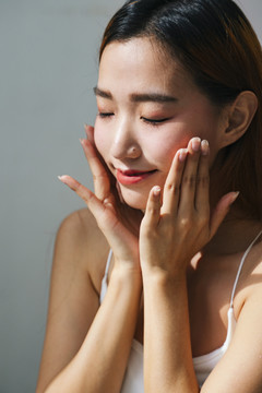 特写肖像画-年轻的亚洲女性用乳液或水洗脸。