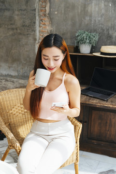 年轻的亚洲女性喜欢喝咖啡，在社交媒体上看一些有趣的节目。