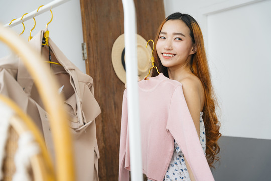 美丽的年轻亚洲女人在购物中心买衣服。