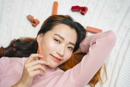 顶视图-美丽的亚洲女性，穿着粉色毛衣，涂着唇膏。