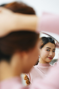 美丽的亚洲女人在镜子前系着头发的肖像。