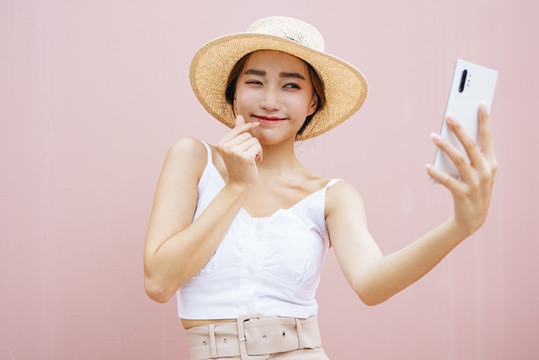 美丽的年轻亚洲女性用智能手机进行视频聊天和直播。