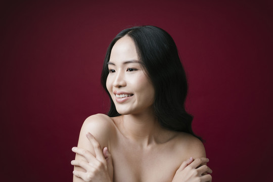 美丽的亚洲年轻女子的肖像，黑色头发，完美的皮肤，干净的红色背景。