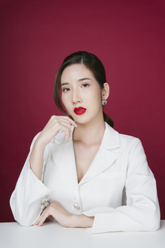 美丽的亚洲年轻女子的画像，涂着红色的口红，穿着白色西装外套。