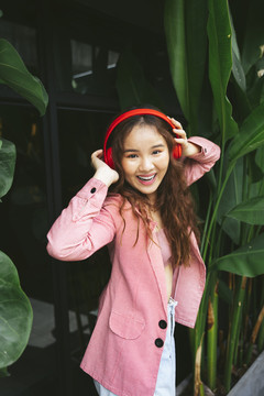 亚洲年轻女子的肖像，喜欢戴着耳机听音乐，带着有趣的表情跳舞。