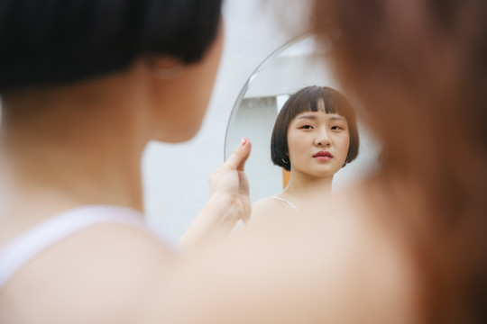 亚洲年轻短发女人照镜子。