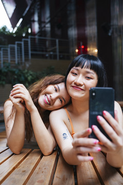 两位年轻亚洲女性一起用智能手机自拍的照片。