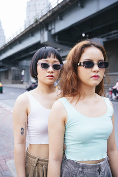 两位在街上戴太阳镜的时髦年轻亚洲女性的特写照片。