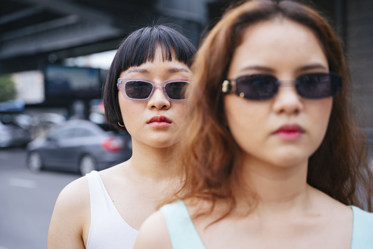 两位在街上戴太阳镜的时髦年轻亚洲女性的特写照片。